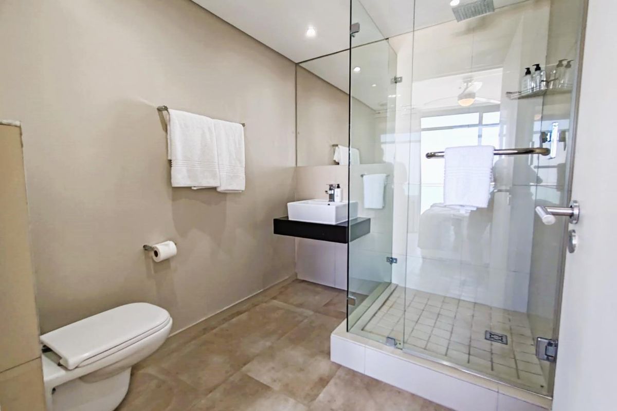 Modern bathroom featuring a glass-enclosed walk-in shower, wall-mounted vanity with basin, and a contemporary toilet.