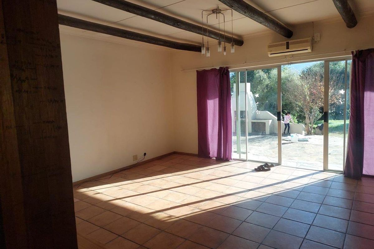 Spacious living area featuring exposed timber ceiling beams, terracotta floor tiles, and large sliding glass doors providing direct access to the outdoor patio.