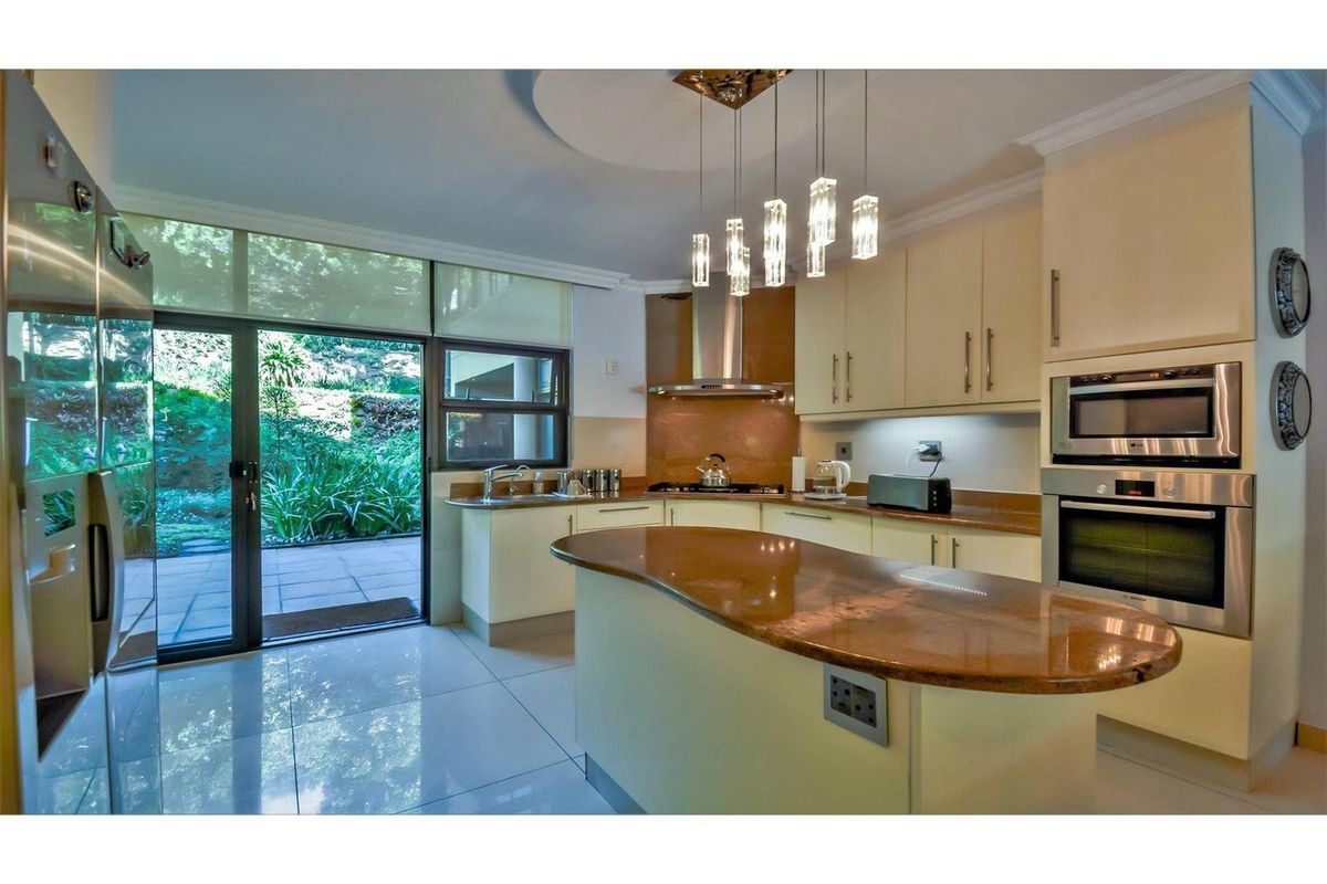 Modern kitchen featuring granite countertops, built-in oven and microwave, sleek cabinetry, and direct access to a private patio area.