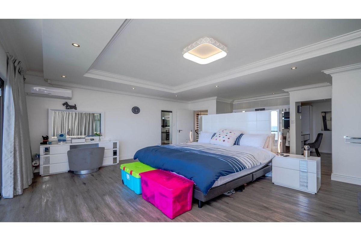 Spacious primary bedroom featuring recessed tray ceiling lighting, modern laminate flooring, and an integrated air conditioning unit.