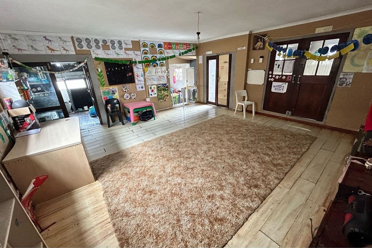 A spacious, multi-purpose room featuring tiled flooring and multiple access points, currently utilized as a learning or activity space.