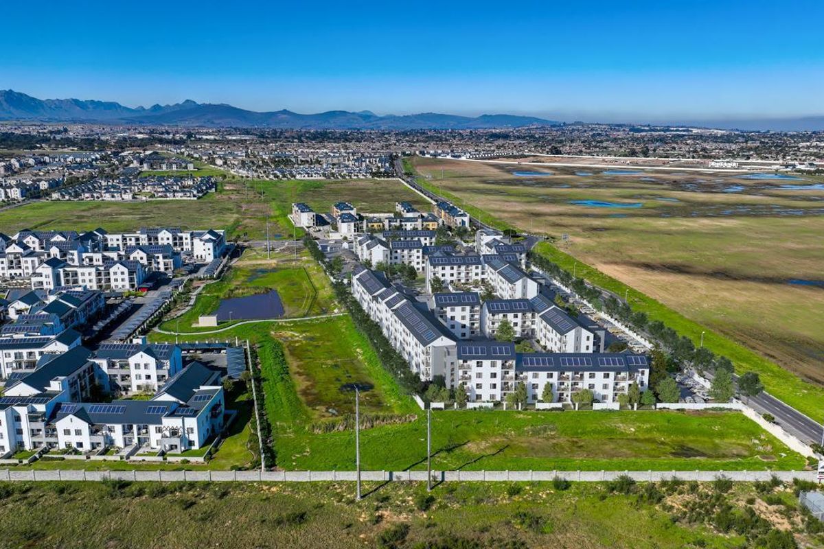 Aerial view of a modern retirement village complex featuring multiple residential blocks, solar installations, and surrounding landscaped green spaces.