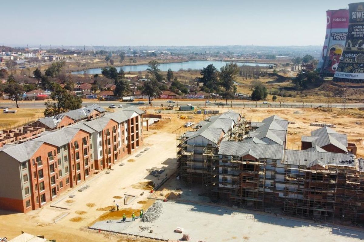 Aerial view of a residential apartment development under construction, featuring multi-story brick buildings and surrounding site infrastructure.