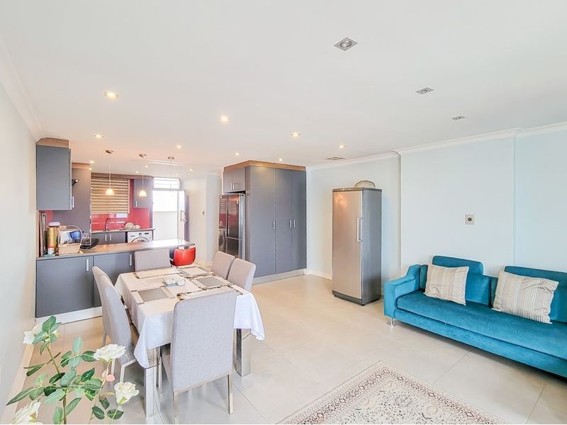 Spacious open-plan living and dining area featuring a modern kitchen with built-in cabinetry, a central island, and neutral tiled flooring throughout.