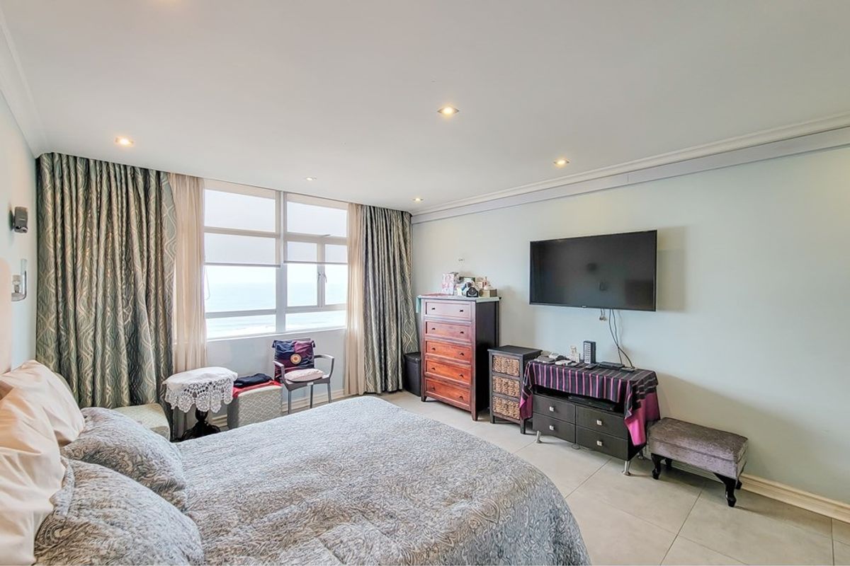 A spacious bedroom featuring tiled flooring, recessed lighting, and large windows with ocean views, offering a bright and comfortable living space.