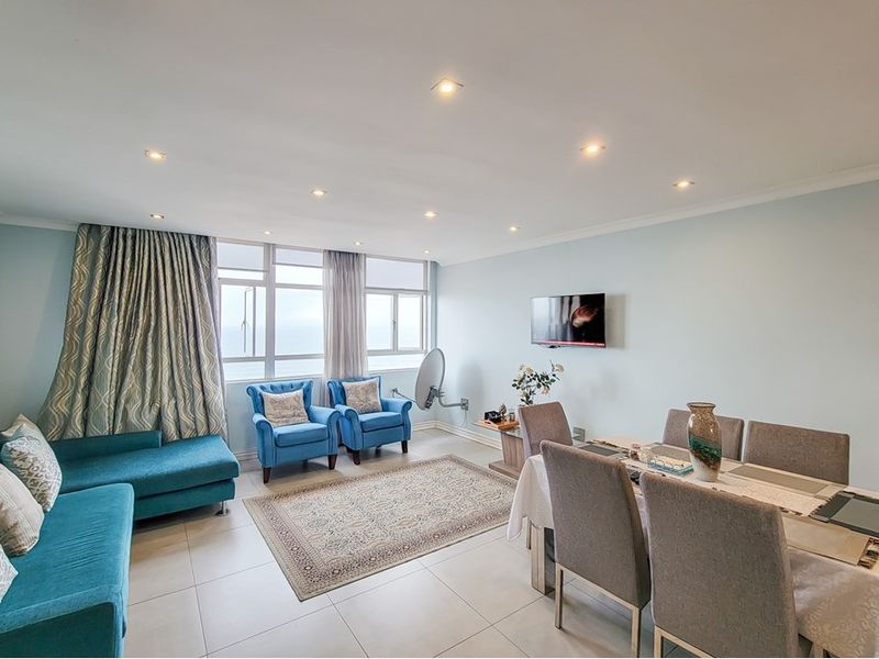 Spacious open-plan living and dining area featuring neutral tiled flooring, recessed downlighting, and large windows providing ample natural light.
