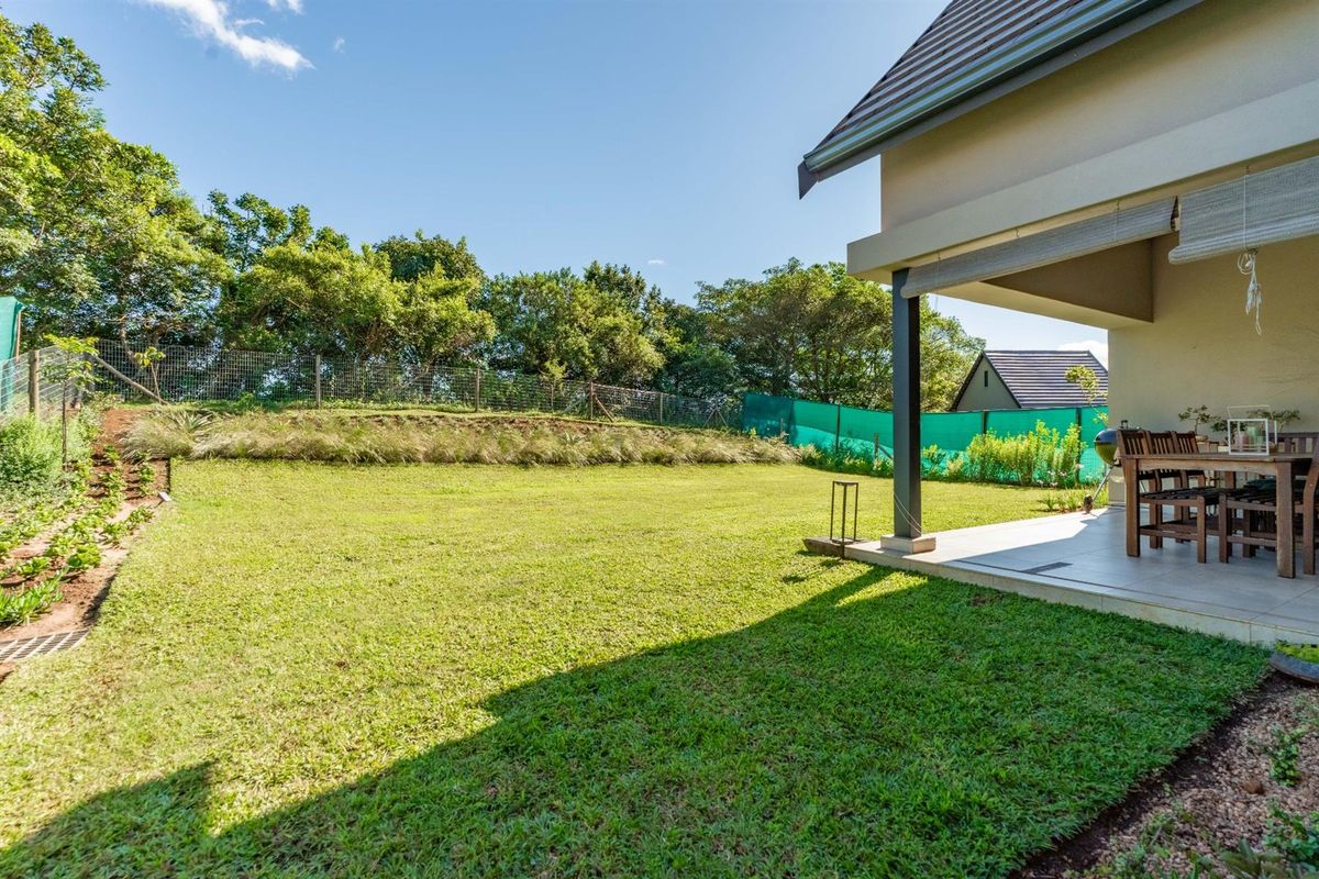 A well-maintained rear garden featuring a spacious lawn, landscaped borders, and a covered patio area perfect for outdoor relaxation.