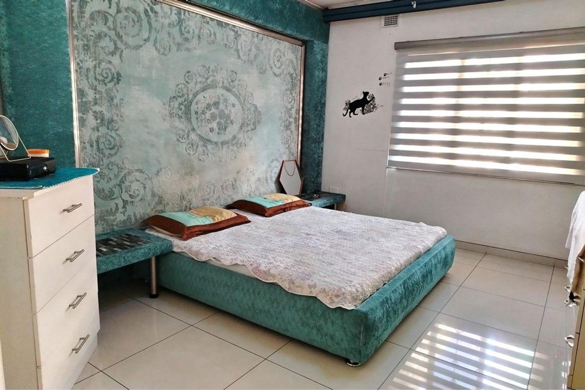 A bedroom featuring tiled flooring, a large decorative feature wall panel, and fitted window blinds.