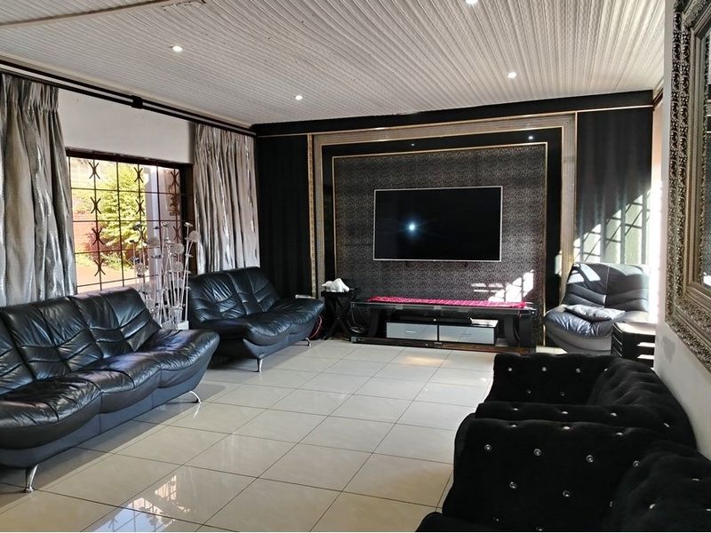 Spacious living room featuring large format floor tiles, a decorative feature wall with integrated television mount, and recessed downlighting.
