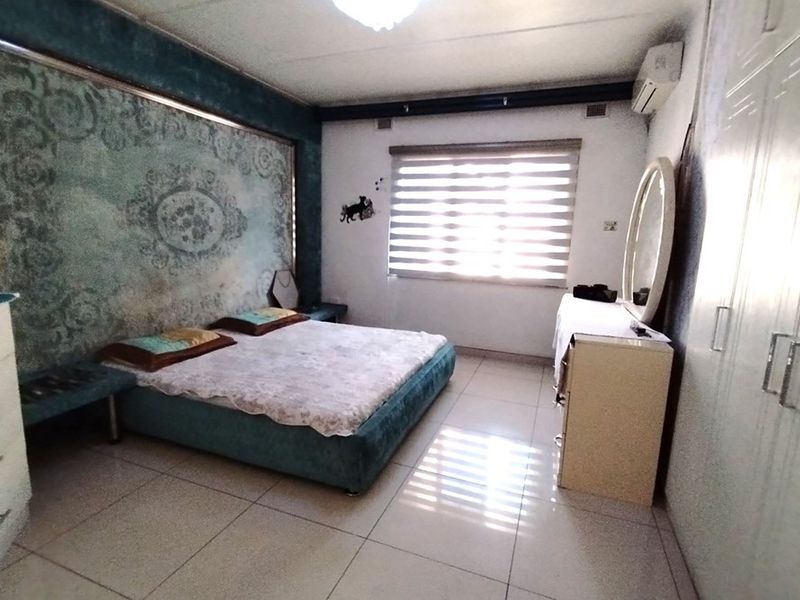 A bedroom featuring tiled flooring, built-in cupboards, and a wall-mounted air conditioning unit.