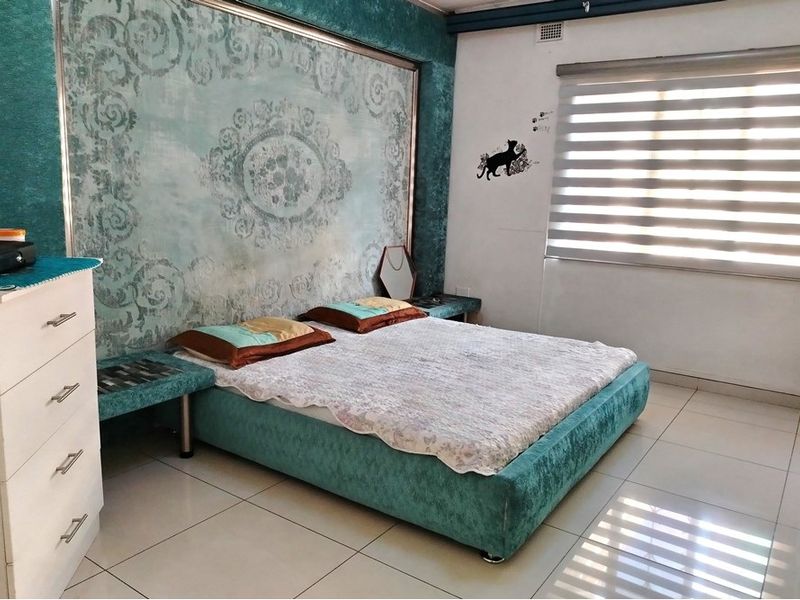 A bedroom featuring tiled flooring, a large decorative feature wall panel, and fitted window blinds.