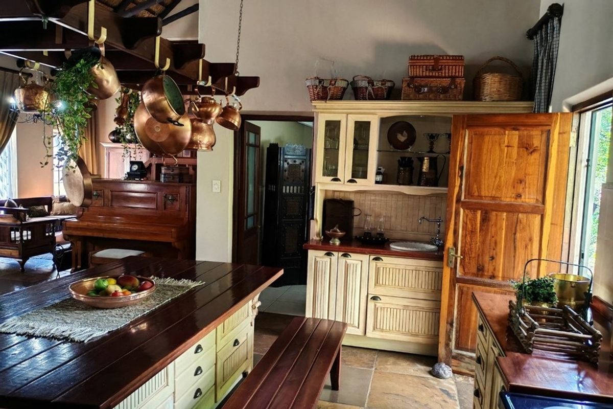 A rustic-style kitchen featuring a central wooden island, built-in cabinetry with a small prep sink, and exposed timber ceiling beams.