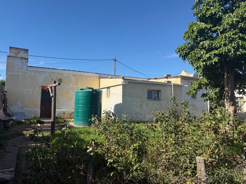 Rear view of the property showing the exterior wall, a water storage tank, and the garden area.