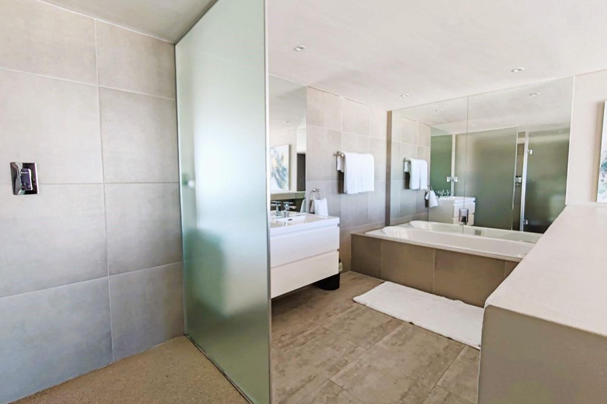 Modern bathroom featuring a large soaking tub, a glass-enclosed shower, and a sleek vanity with integrated mirror.