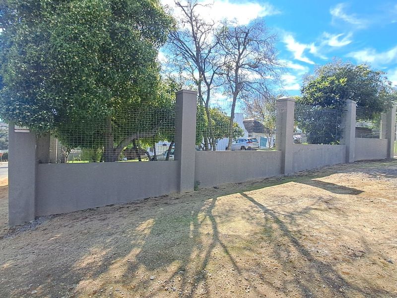 A view of the property boundary featuring a solid perimeter wall with integrated concrete pillars and wire mesh fencing.