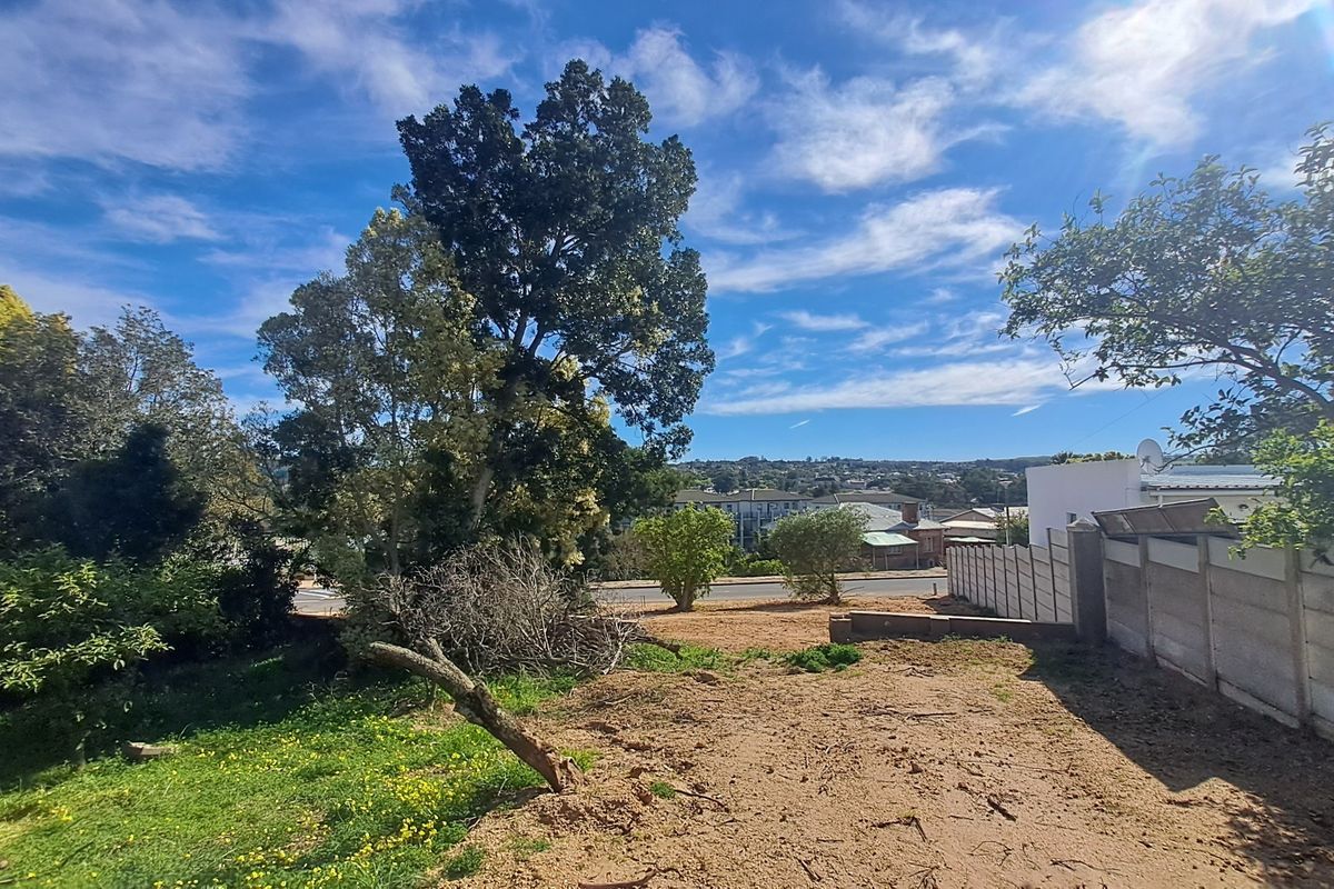 A view of a vacant residential plot featuring a precast concrete boundary wall and established trees, offering potential for future development.