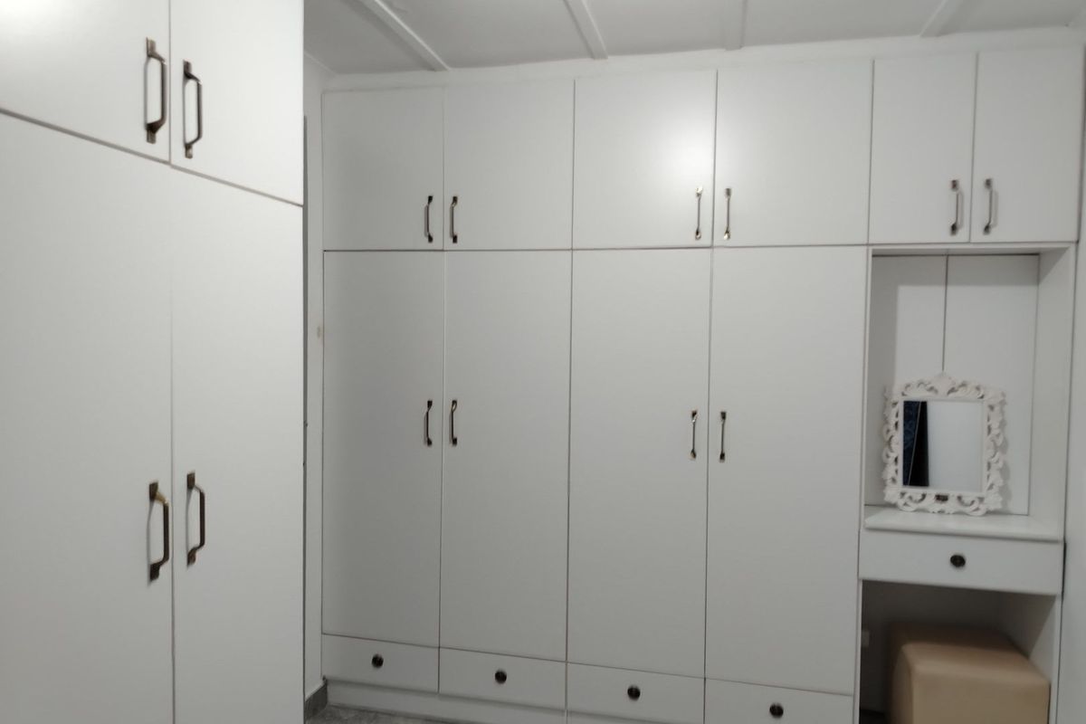 A bedroom featuring extensive white built-in cabinetry with integrated storage and a dedicated vanity area.