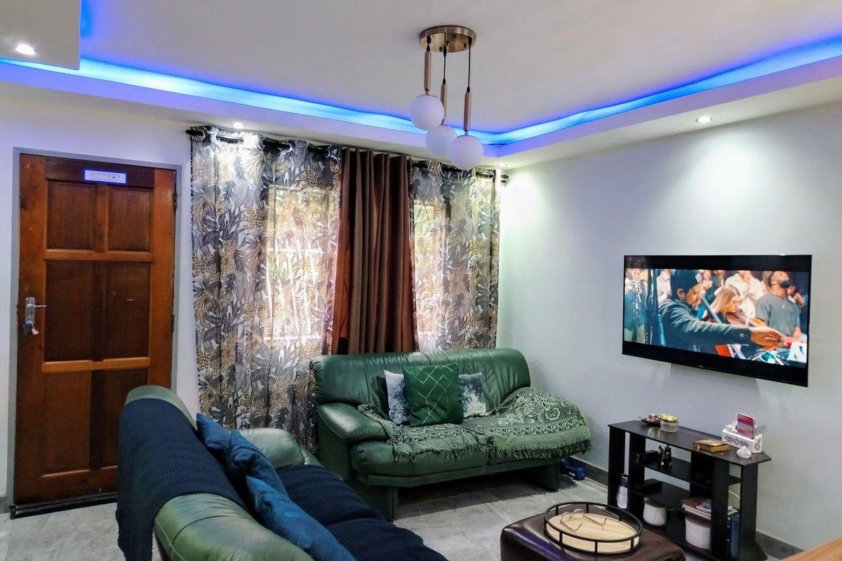 A cozy living room featuring modern recessed ceiling lighting with blue accent cove lighting and tiled flooring.