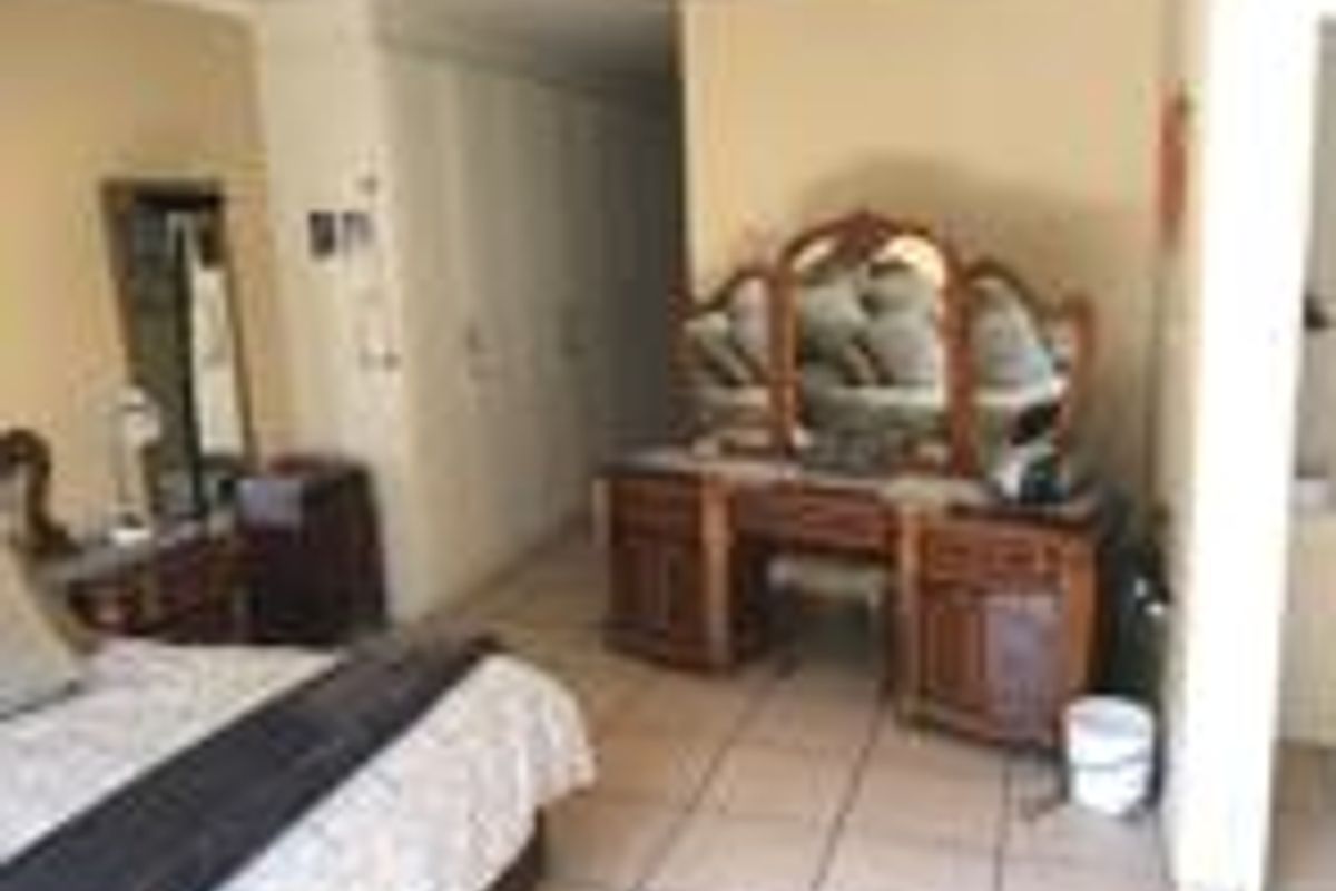 A bedroom featuring tiled flooring and built-in cupboards, providing ample storage space.