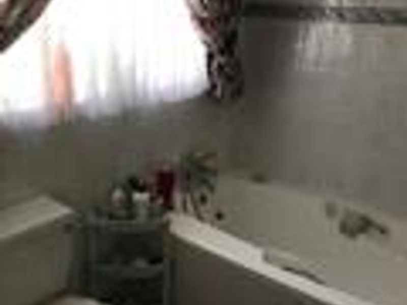A functional bathroom featuring a built-in bathtub and a standard toilet, finished with wall tiling.