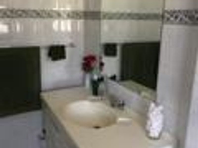 A functional bathroom vanity featuring a built-in sink, countertop, and wall-mounted mirror with tiled wall finishes.