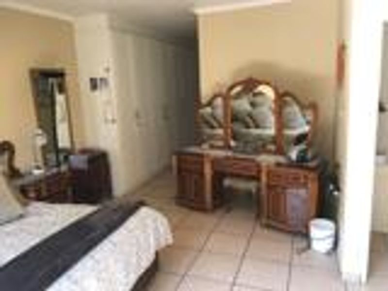 A bedroom featuring tiled flooring and built-in cupboards, providing ample storage space.
