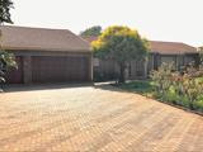 Front exterior view of the house featuring a paved driveway, double garage, and established garden.