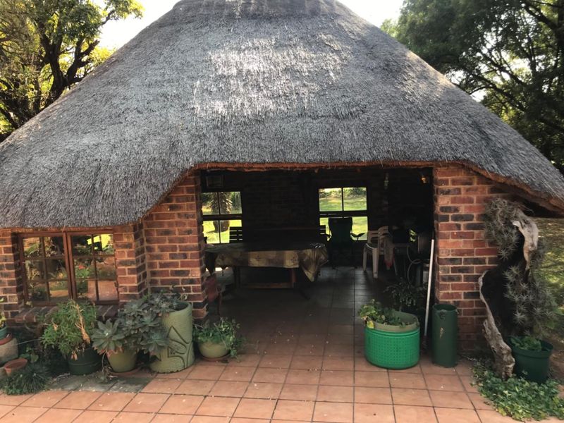 A rustic outdoor entertainment area featuring a traditional thatched roof and exposed brick construction, providing a covered space for relaxation and social gatherings.
