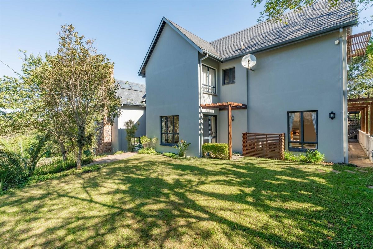 Rear view of the two-story house featuring a well-maintained lawn, timber pergola, and established garden landscaping.