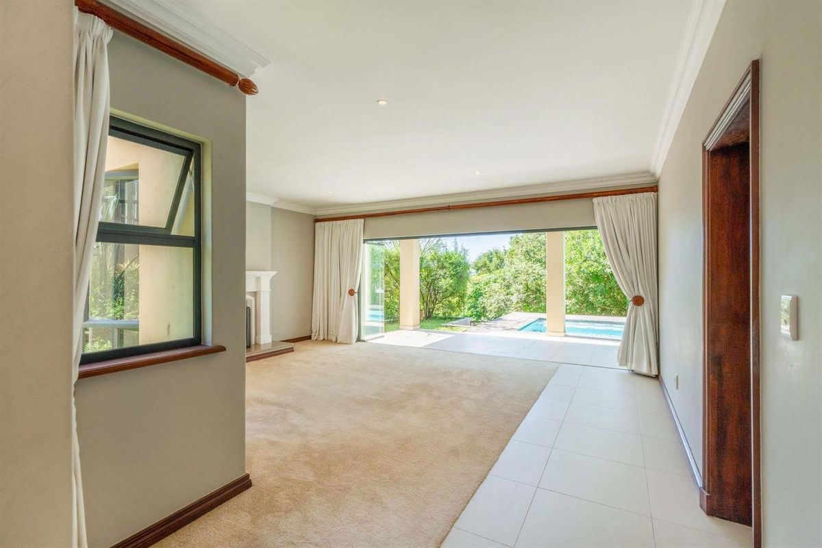 Spacious living area featuring neutral carpeting, a fireplace, and large sliding doors that open onto a covered patio and swimming pool area.