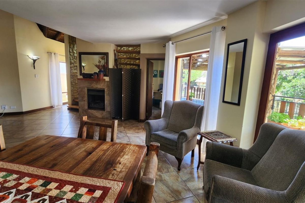 A living room featuring tiled flooring, a stone fireplace, and a sliding glass door providing access to an outdoor area.