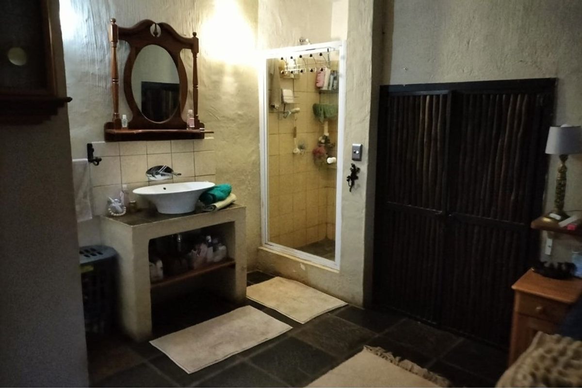 A rustic-style bathroom featuring a vessel sink on a built-in vanity, a separate shower enclosure, and dark stone floor tiles.