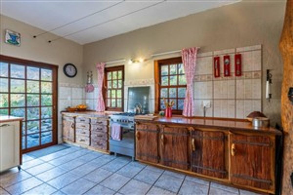 A rustic kitchen featuring wooden cabinetry, tiled countertops, a freestanding gas stove, and direct access to the outdoors through a glass-paned door.