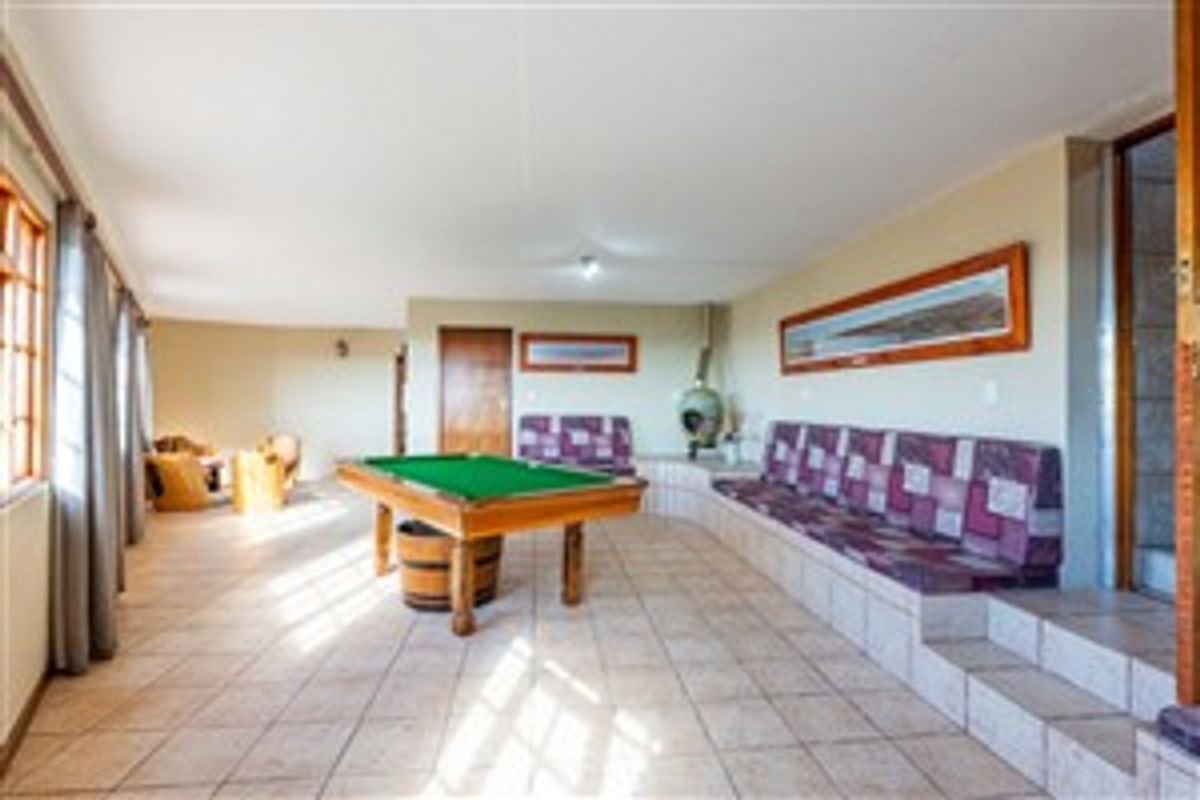 Spacious entertainment room featuring built-in bench seating, tiled flooring, and a freestanding fireplace, ideal for a games area or casual living space.