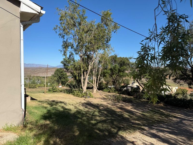 A view of the rear garden area featuring established trees, a washing line, and distant mountain views.