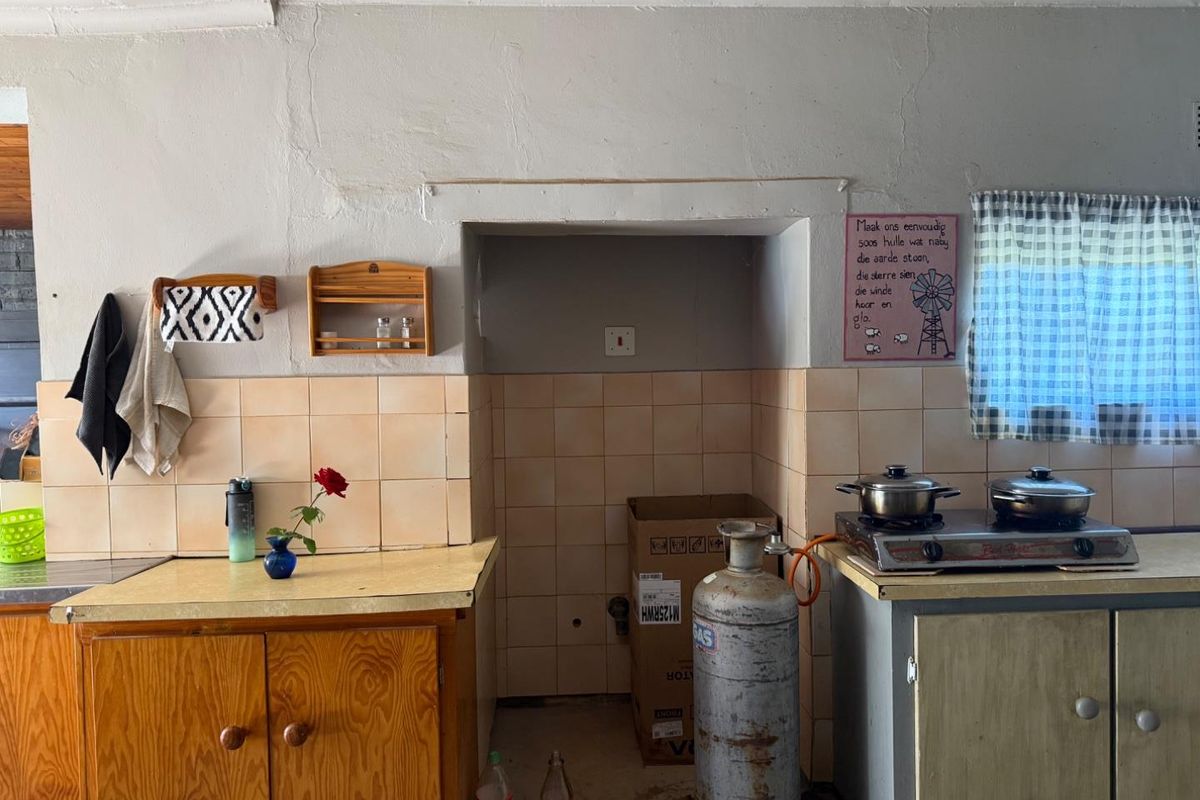 A dated kitchen area featuring wooden cabinetry, tiled splashbacks, and a gas hob setup, requiring modernization and improved finishings.