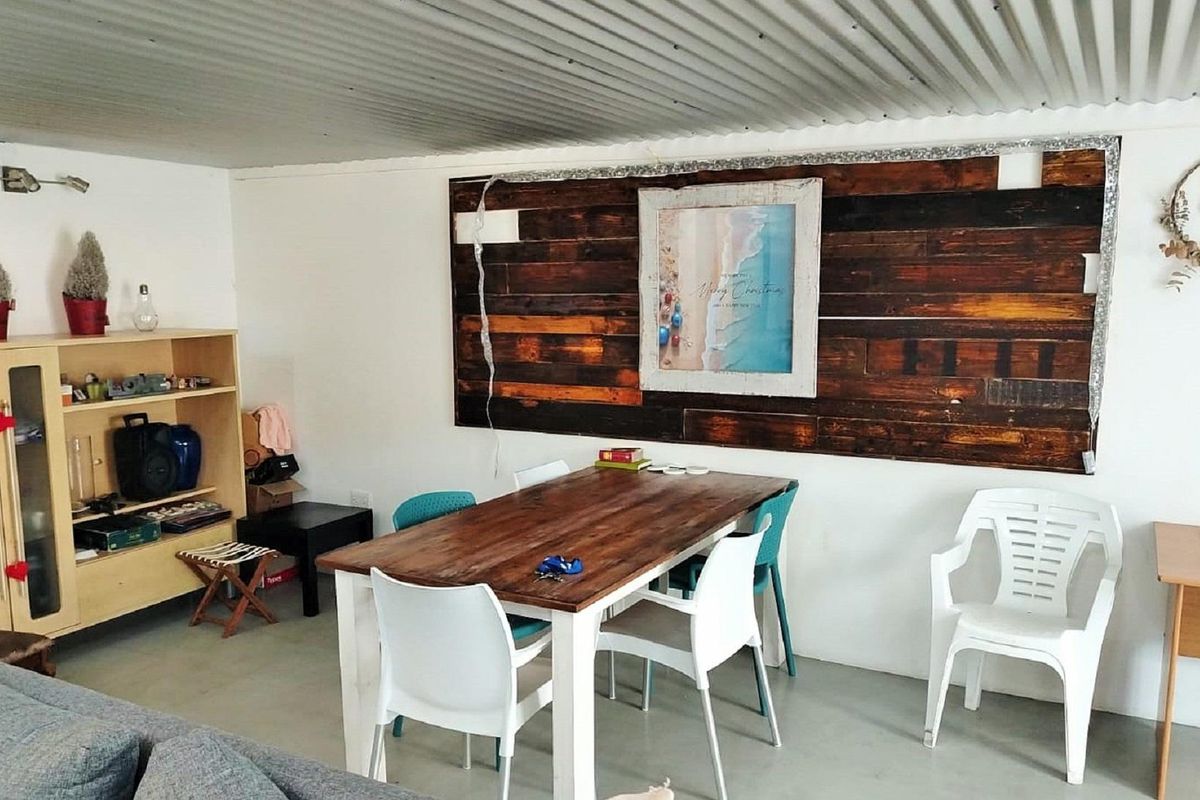 A casual dining area featuring a rustic wood-paneled feature wall and a corrugated metal ceiling, providing a simple, functional space.