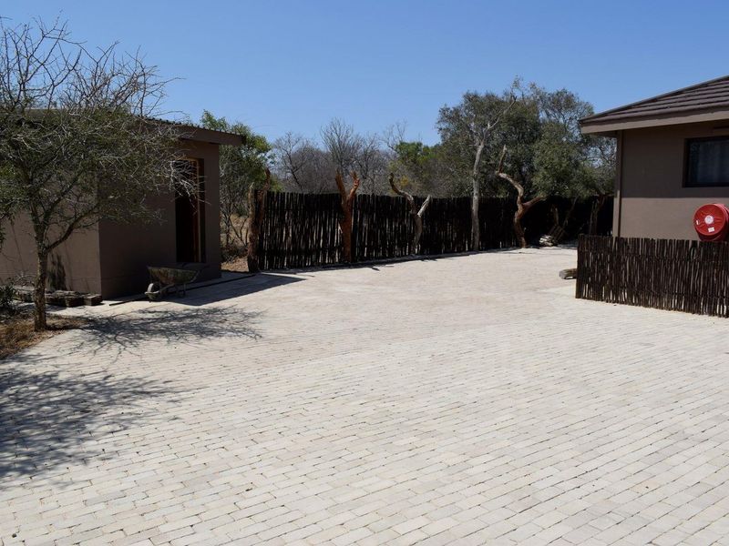 A paved rear courtyard area featuring timber pole fencing and exterior building structures.