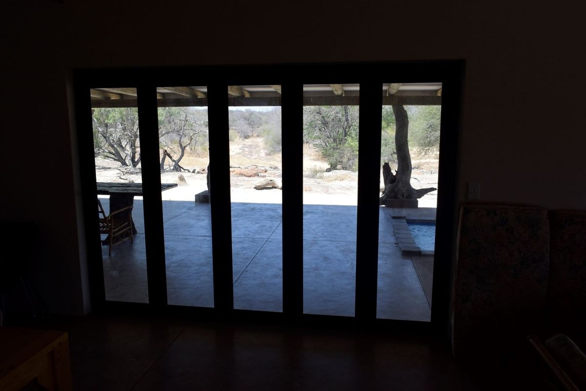 Interior view looking out through large bi-fold doors onto a covered patio and natural landscape.