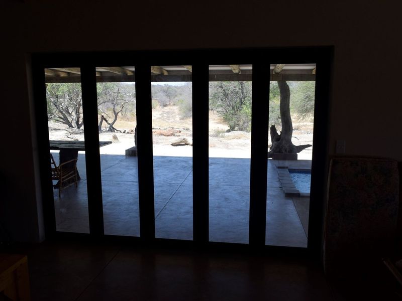 Interior view looking out through large bi-fold doors onto a covered patio and natural landscape.