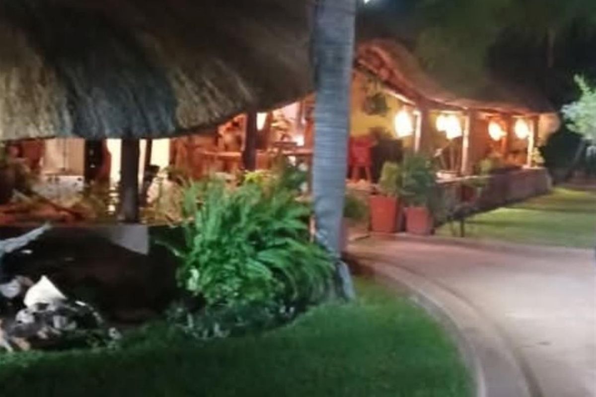 Night view of a farm property featuring a thatched roof structure, paved pathways, and landscaped garden areas.