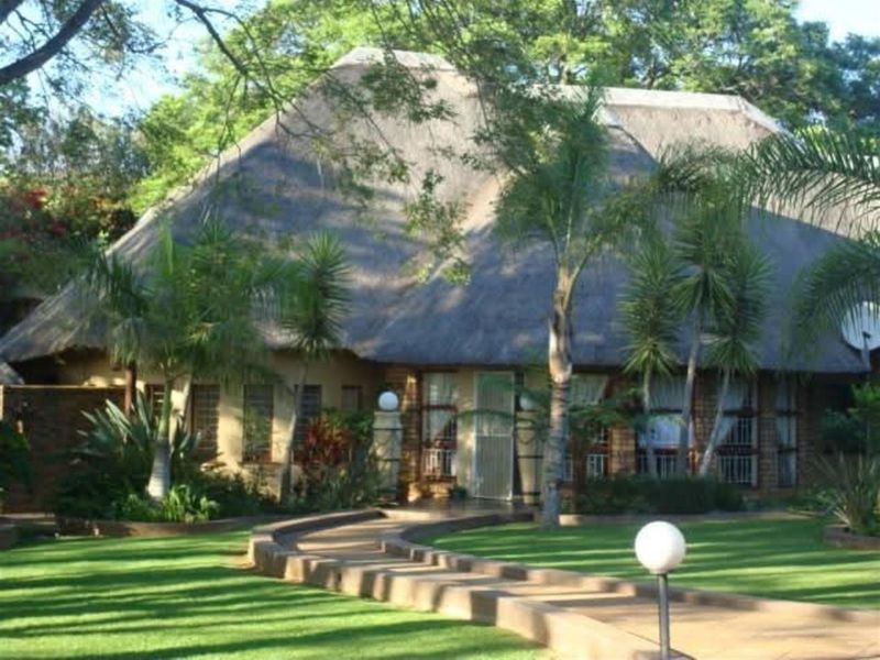 Front view of a charming farm-style residence featuring a traditional thatched roof, brick exterior, and a well-maintained garden with a paved entrance path.