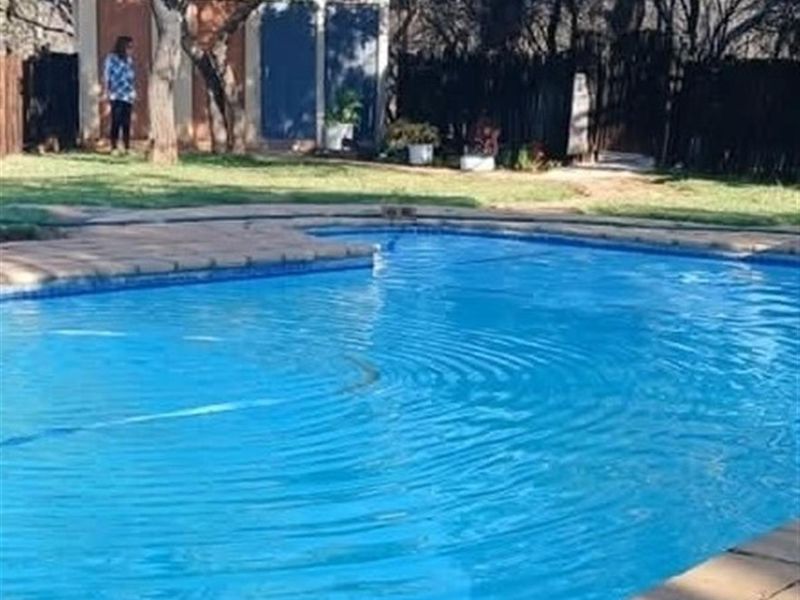 A backyard swimming pool with a paved surround and a small outbuilding visible in the background.