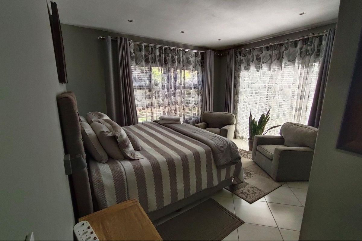A well-maintained bedroom featuring tiled flooring, recessed ceiling lighting, and large windows with integrated curtain tracks.