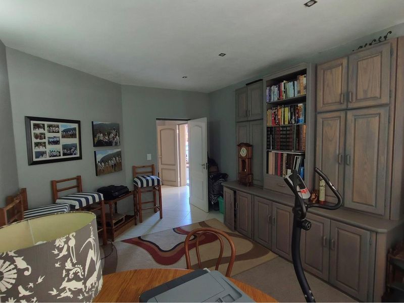 A multi-purpose living space featuring extensive built-in cabinetry and recessed ceiling lighting, providing versatile storage and functional room layout.