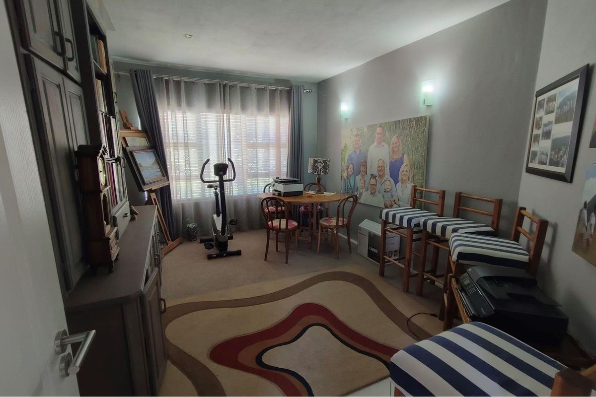 A multi-purpose room featuring wall-mounted lighting and window treatments, currently utilized as a flexible living and hobby space.