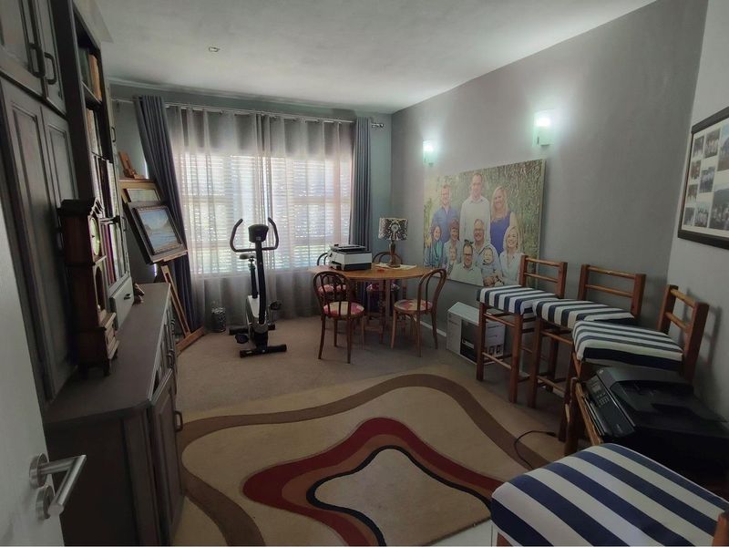 A multi-purpose room featuring wall-mounted lighting and window treatments, currently utilized as a flexible living and hobby space.