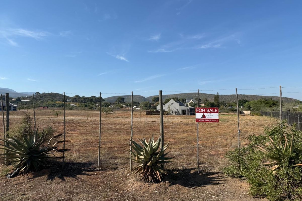 A vacant residential plot featuring perimeter wire fencing, established aloe plants, and scenic mountain views, currently available for sale.