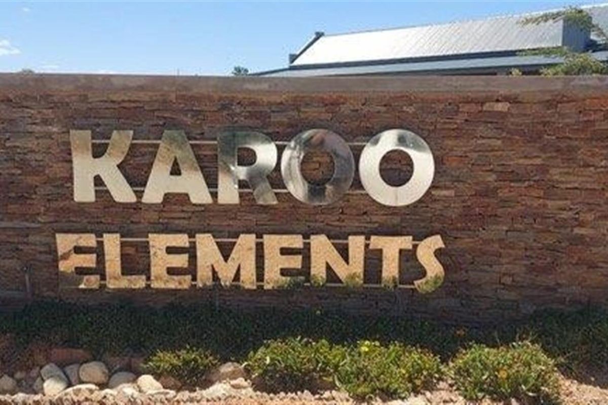 A stone-clad entrance monument sign for Karoo Elements, featuring polished metal lettering and integrated landscaping.