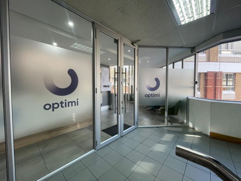 Modern office entrance featuring glass partition walls with frosted branding, aluminium frames, and clean tiled flooring.